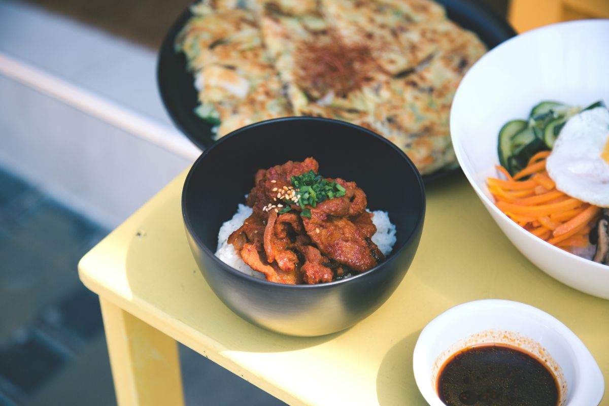 sepiring nasi dengan daging dan makanan pelengkap lain