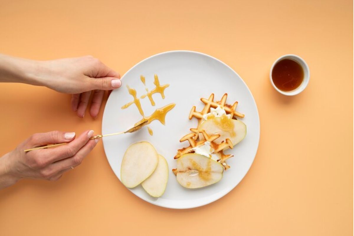 Sepiring buah dengan madu dan wafel dan secangkir teh