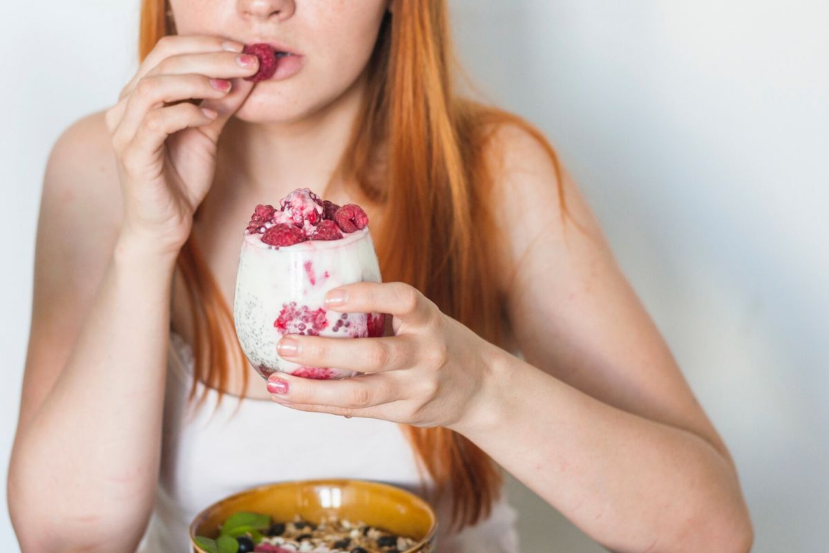 Seorang wanita memakan yogurt raspberry