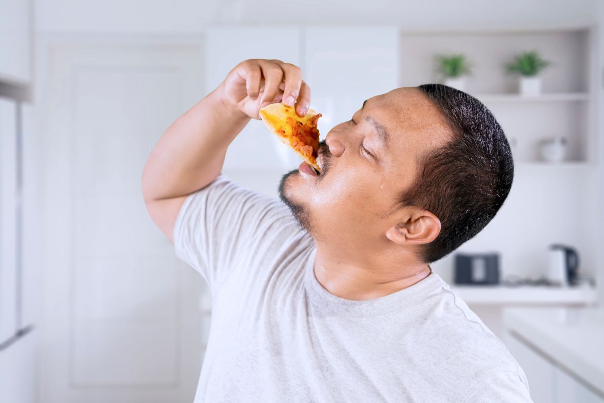 Seorang pria sedang makan pizza