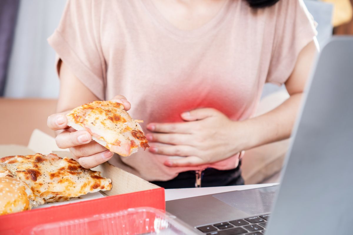 Seorang wanita sedang memakan makanan yang menyebabkan asam lambung