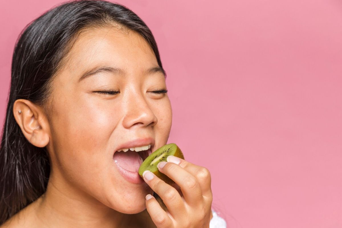 Seorang wanita memakan kiwi
