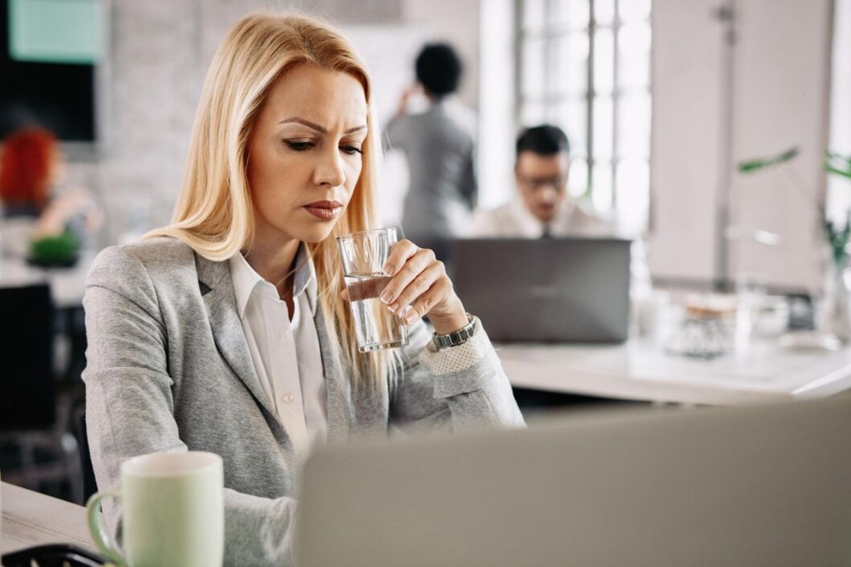 Perempuan minum air putih di kantor