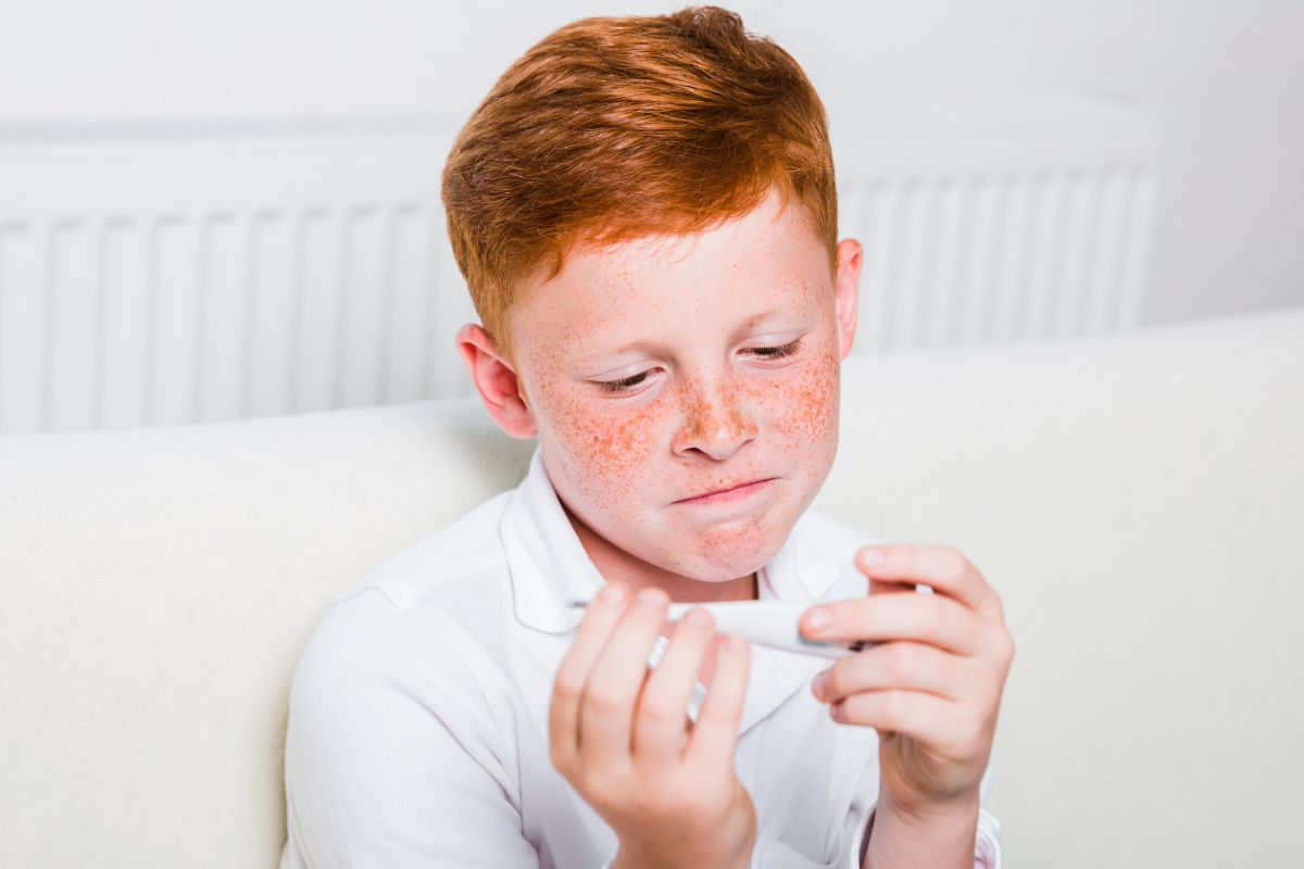 anak yang sedang melihat suhu tubuh di thermometer