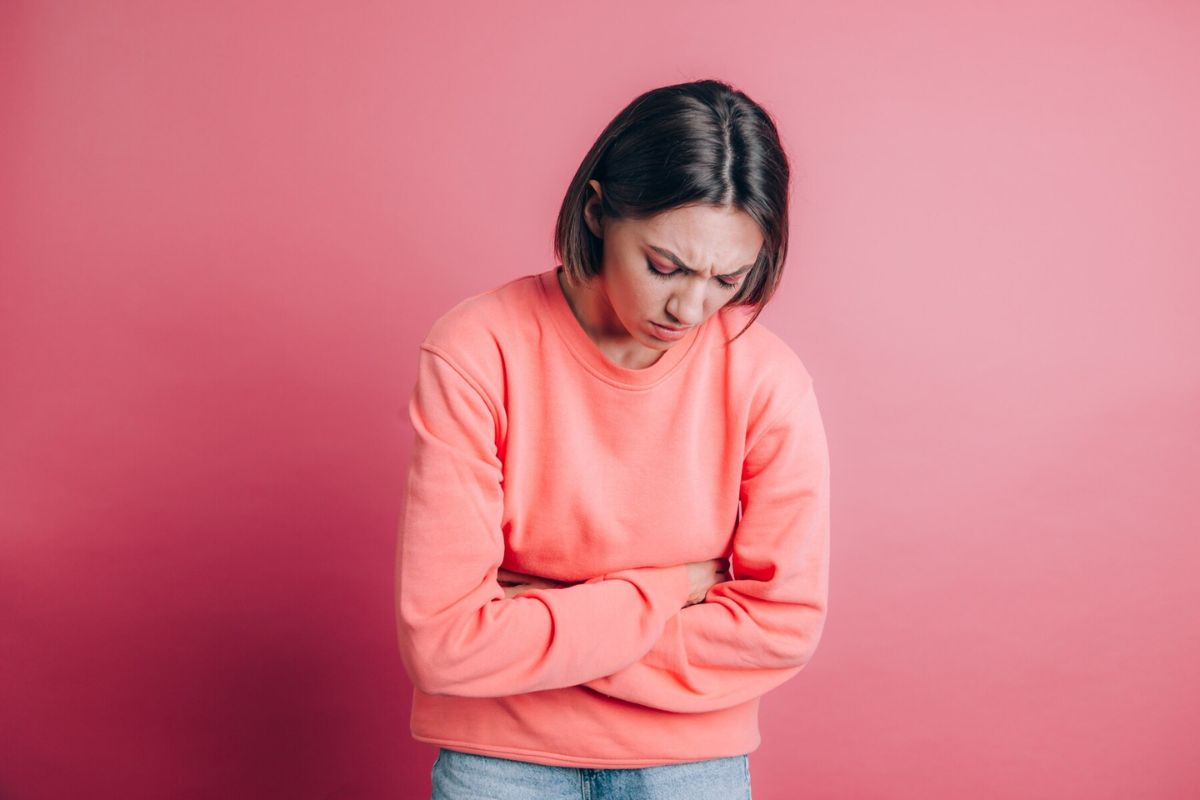 Wanita menderita sakit perut dengan seringai menyakitkan karena menstruasi