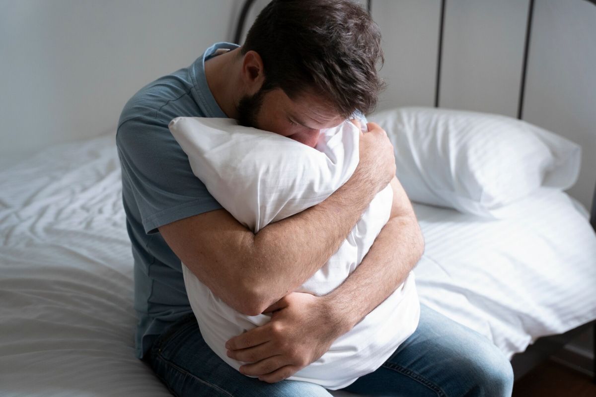 Seorang pria sedang memeluk bantal