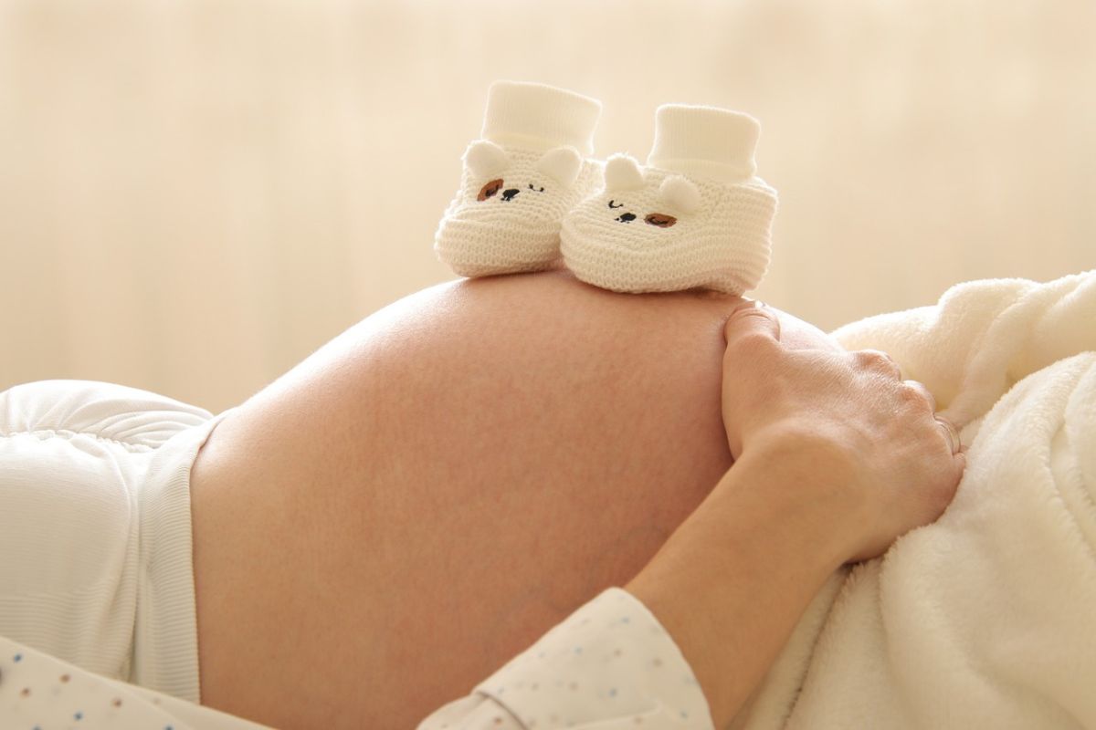 ibu yang menaruh sepatu bayi di atas perut