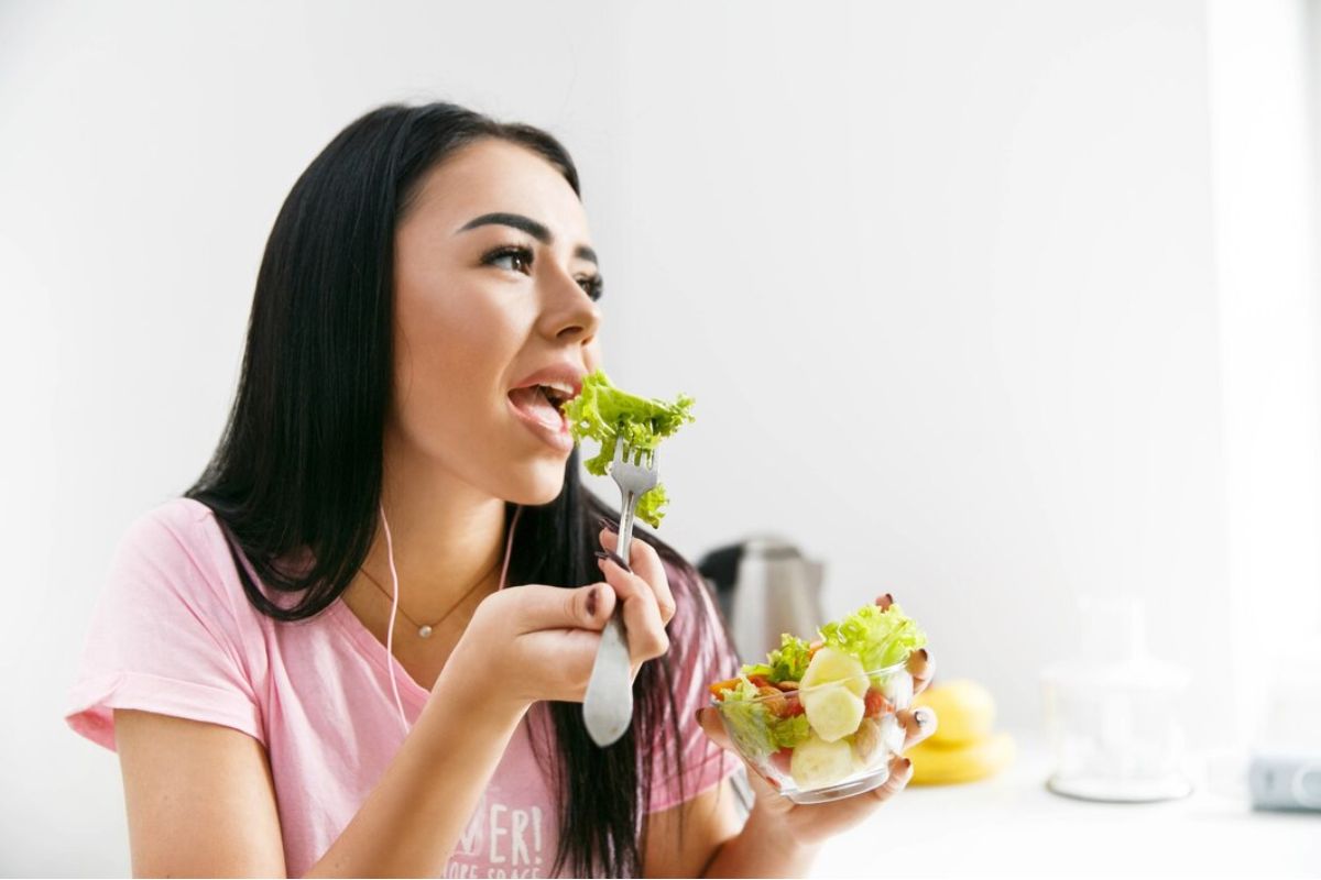 Perempuan makan semangkuk salad segar