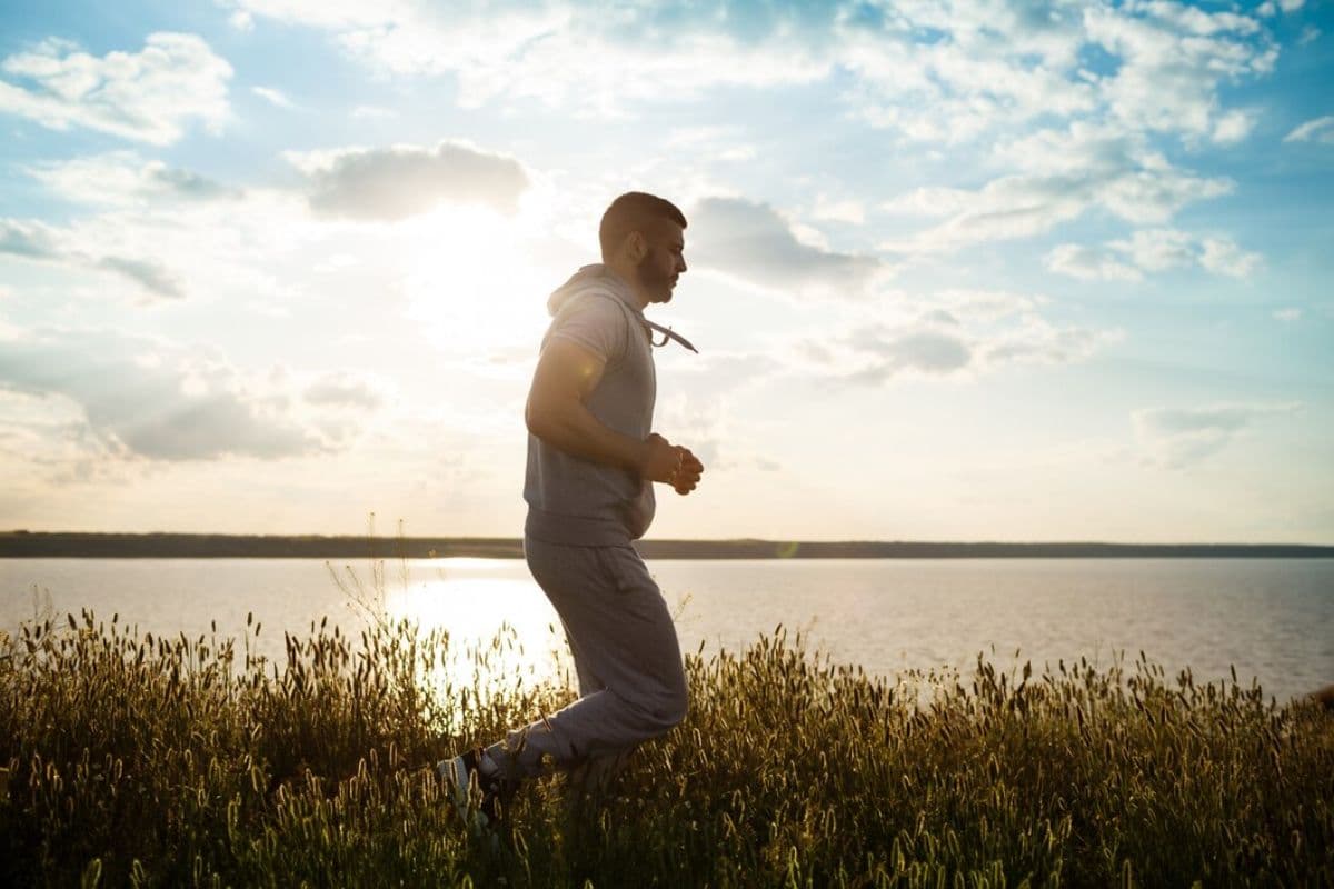 Laki-laki jogging pagi hari di pinggir danau