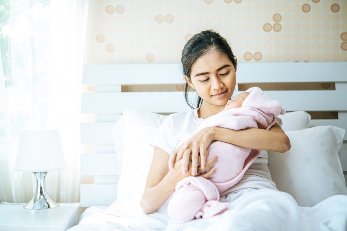 Wanita sedang menggendong bayi yang baru lahir