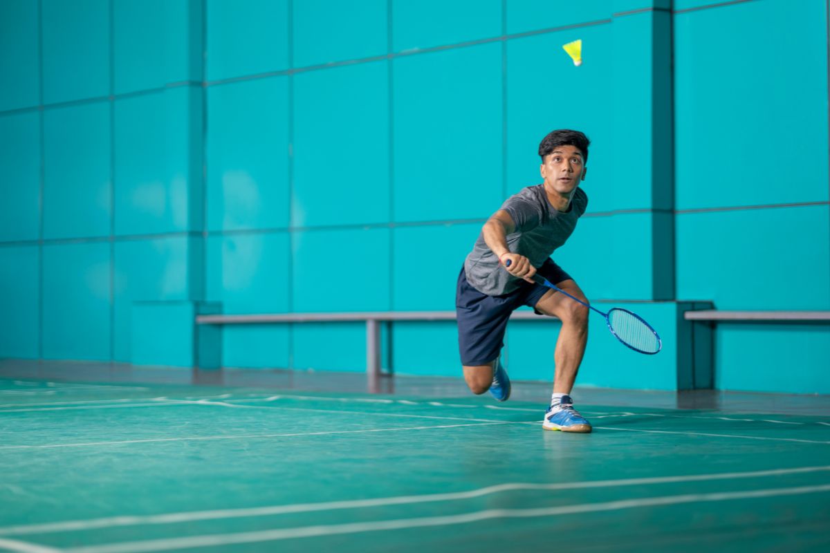 Pria sedang bermain badminton di lapangan