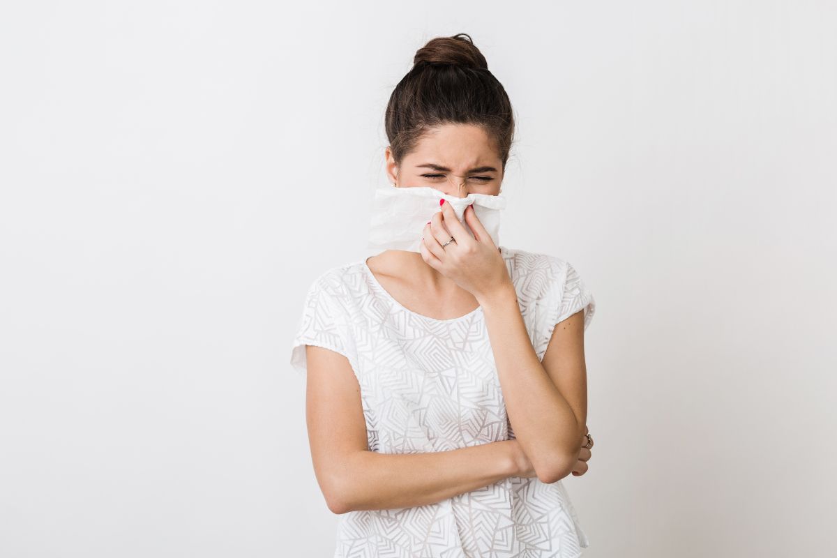 orang yang menutup hidung dengan tisu