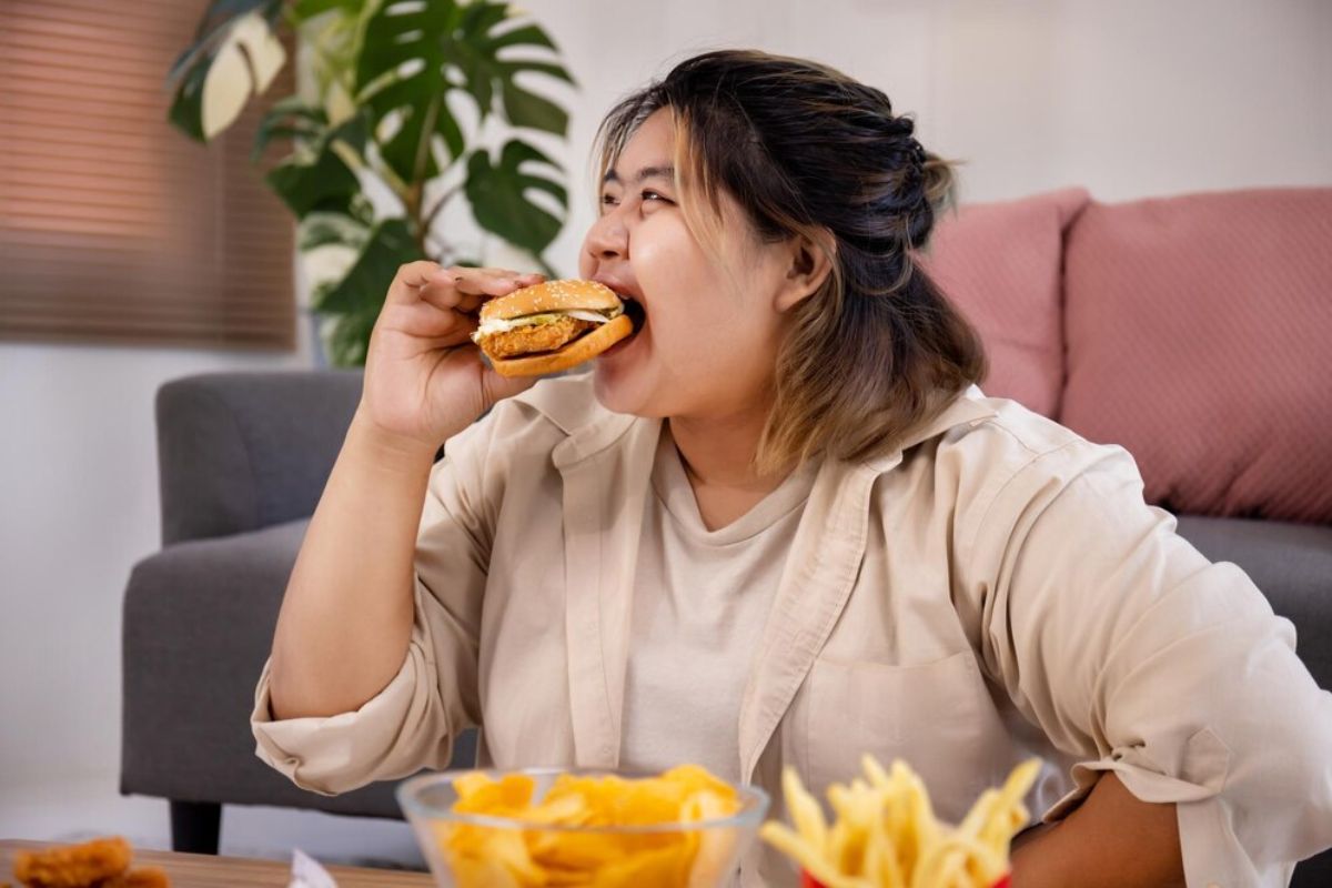 Perempuan makan burger dan makanan cepat saji lainnya