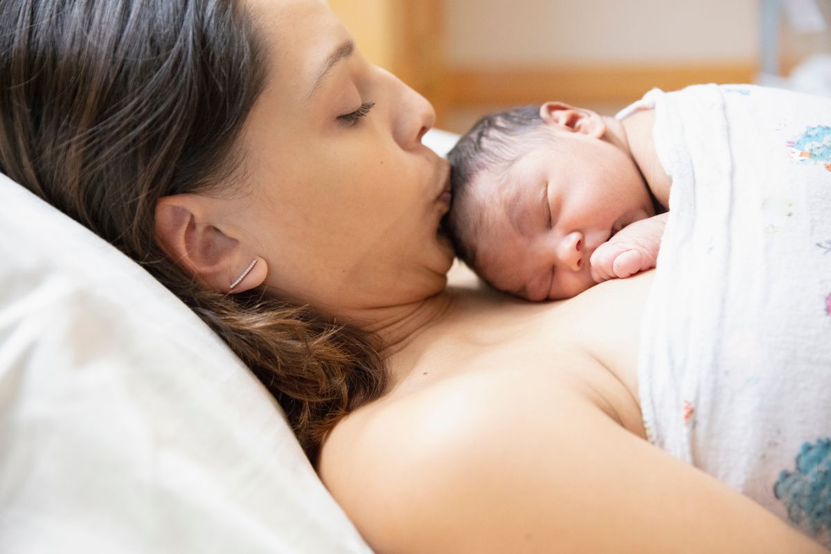 Wanita sedang berbaring dengan bayi baru lahir