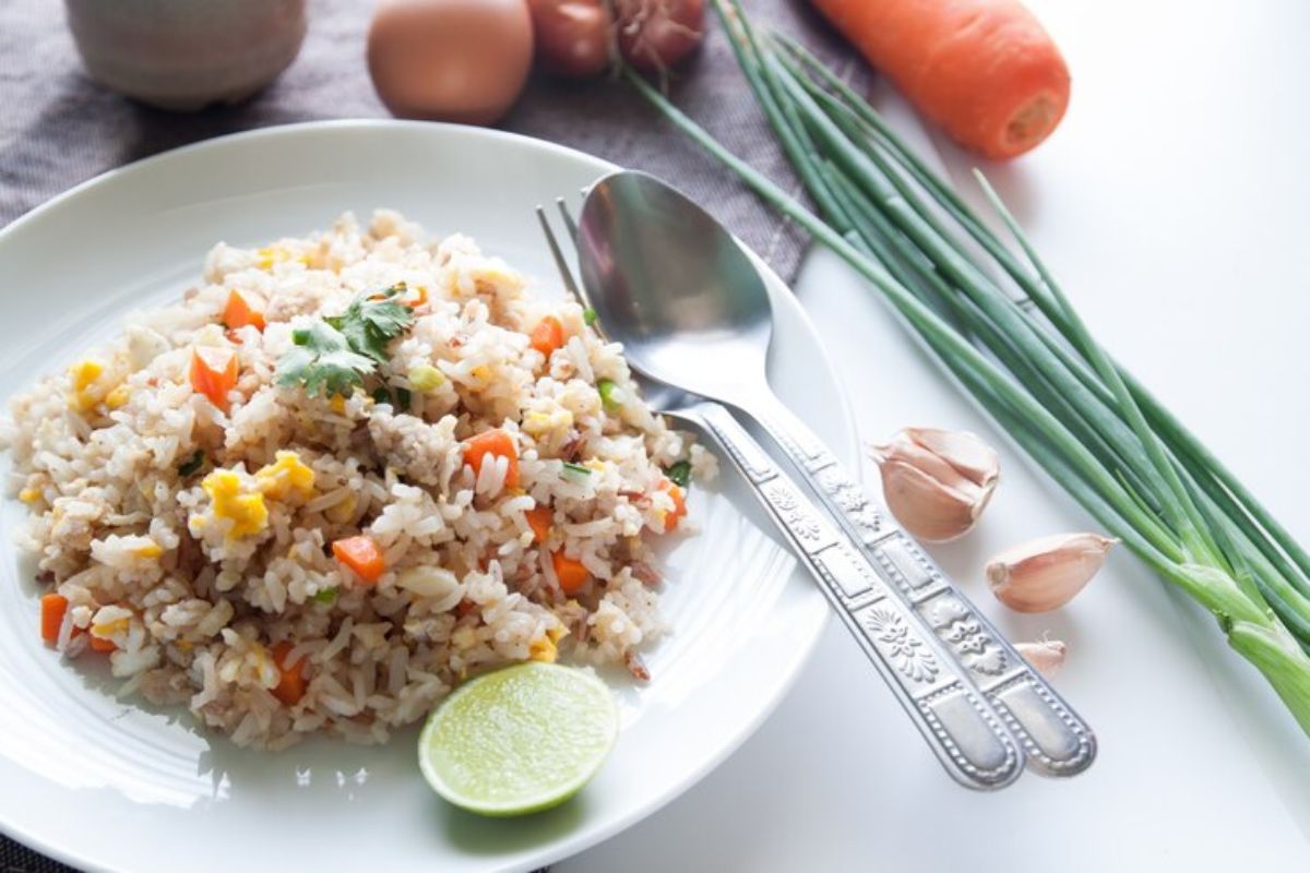 sepiring nasi goreng dengan potongan wortel dan telur dengan sendok garpu