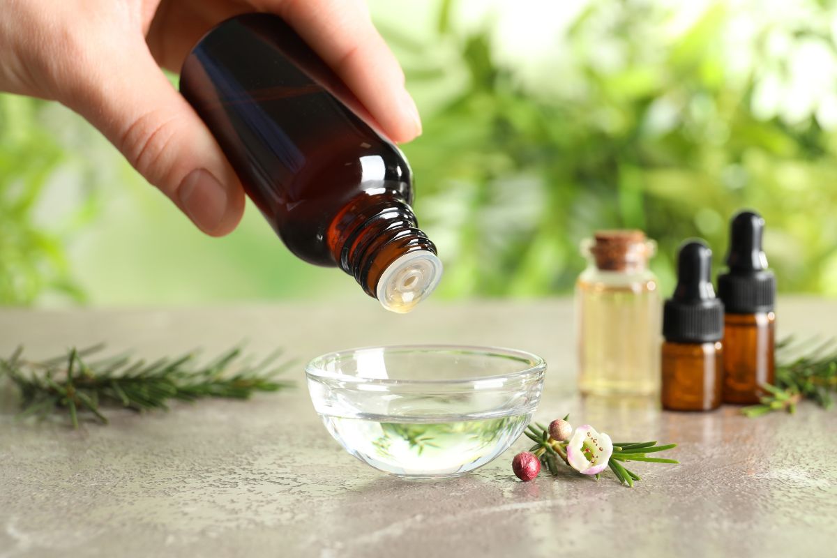 Seseorang menuang tea tree oil ke dalam air di wadah kaca