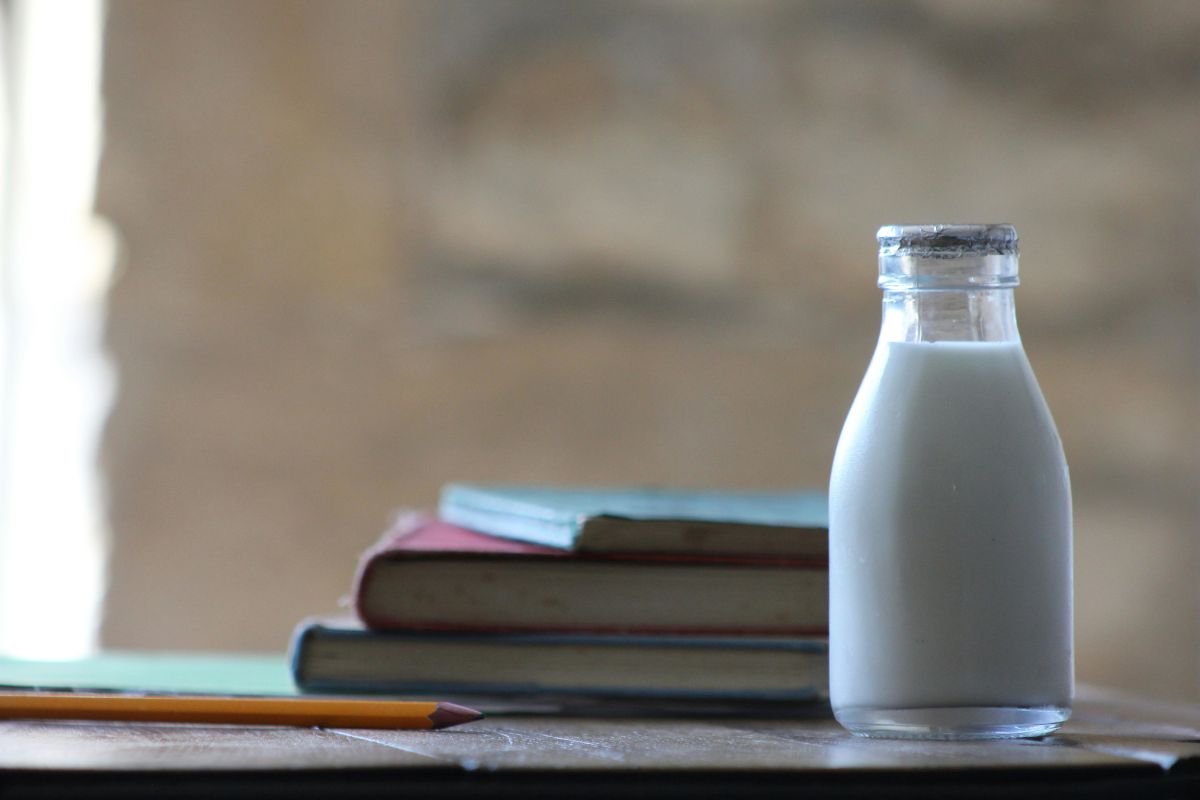 sebotol susu di depan tumpukan buku