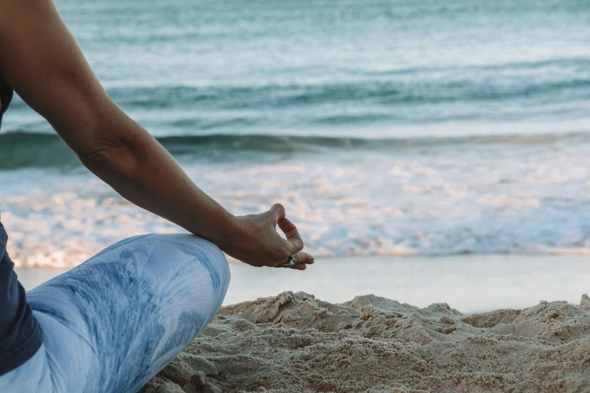 orang yang melakukan yoga di pinggir pantai